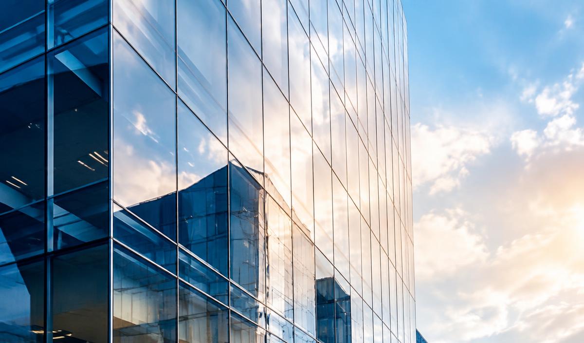 Glass office tower reflecting the sky in a financial district